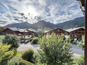 A hotel with multiple wooden buildings, a parking lot, and mountains in the background. - 2nd floor, swimming pool, balcony, tv, ski locker, 40m², Praz sur Arly (Praz-sur-Arly)