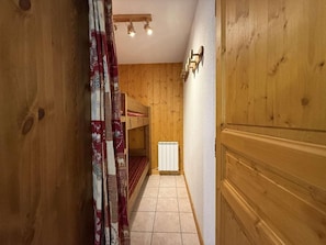 A narrow hallway with wooden walls and a bunk bed in the background. - Ground floor, balcony, tv, ski locker, 35m², Praz sur Arly (Praz-sur-Arly)