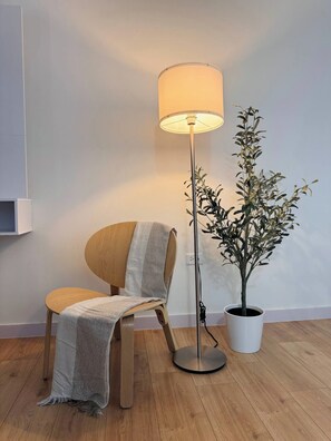 A modern room with a wooden floor, a round chair with a grey throw, a floor lamp, and a potted plant. - Centrally located in historic town of San Germán! (San Germán)
