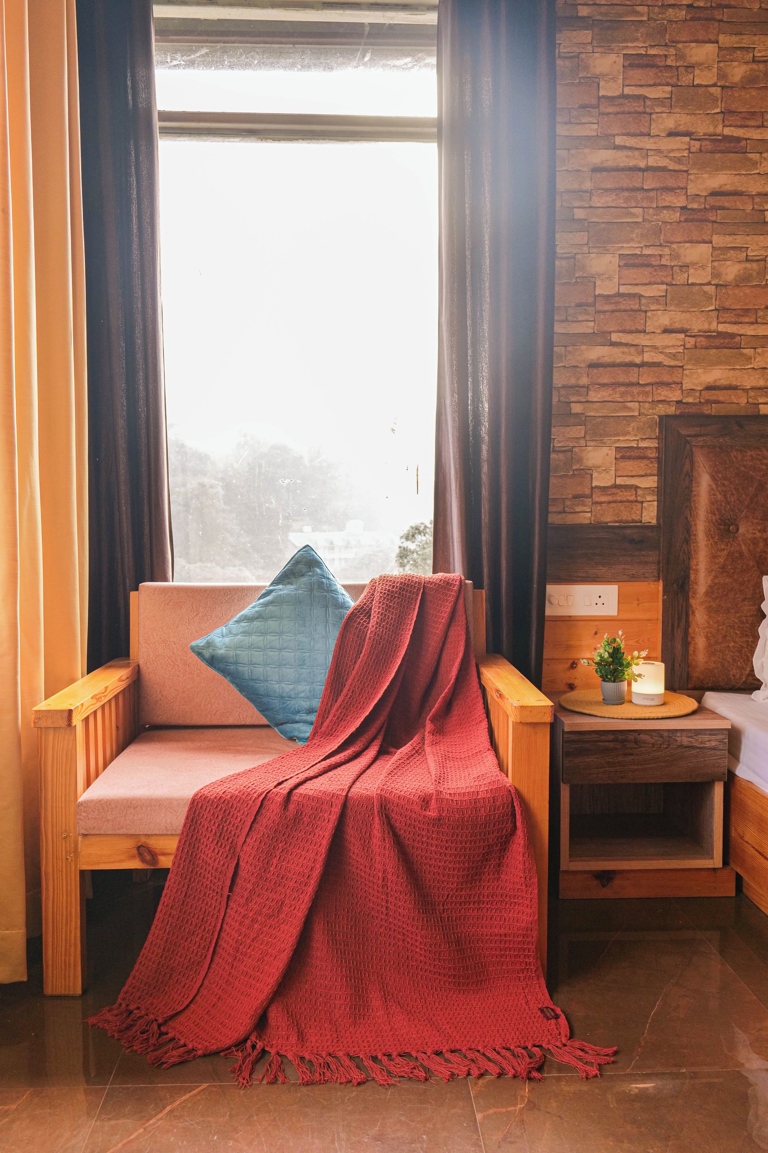 A cozy seating area with a cushioned bench, a red blanket, and a blue pillow.