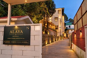 A pathway leading to a building with a signboard for 'ALAYA & BHOWALI' indicating it is a brand of Shivaneel Hospitality Pvt Ltd.