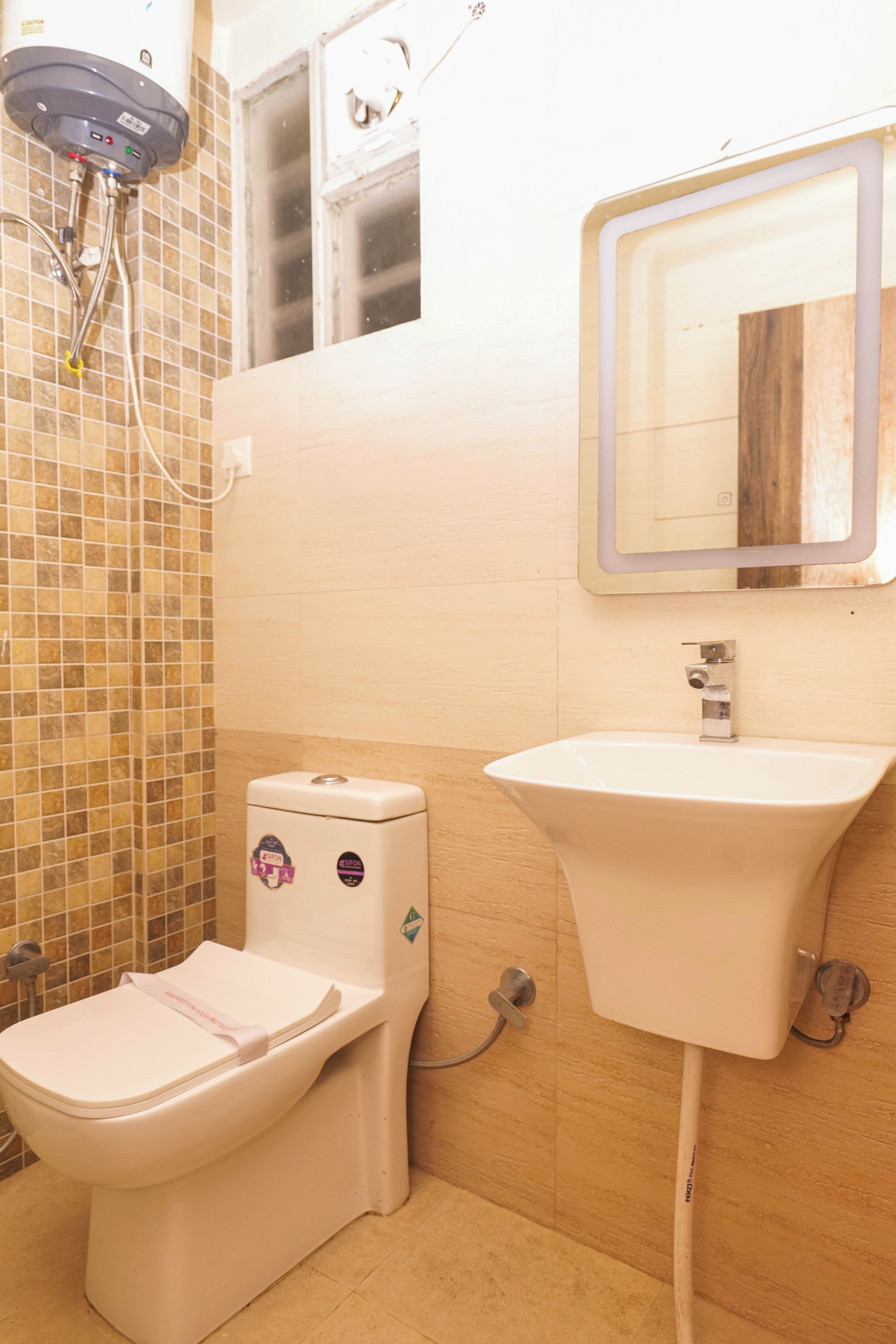 Een badkamer met toilet, wastafel en een douchekop aan de muur.