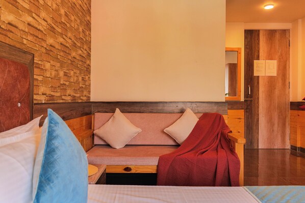 A hotel room with a wooden bench, a bed with pillows, and a wooden door.