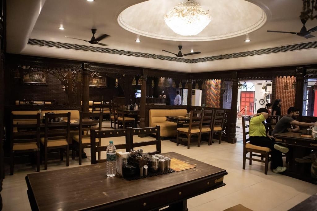 Restaurante com mobiliário de madeira, um candelabro e ventiladores de teto.