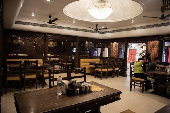 Un restaurante con mobiliario de madera, un candelabro y ventiladores de techo.
