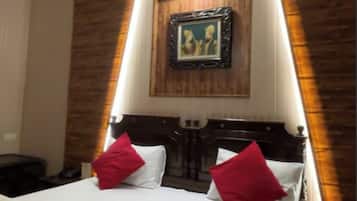 Une chambre d’hôtel avec un lit, un ventilateur de plafond, un tableau encadré au mur et un mur décoratif en bois.