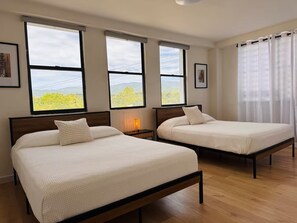 A hotel room with two beds, large windows, and a view of greenery. - Stay Together! Two Apartments in San Germán! (San Germán)