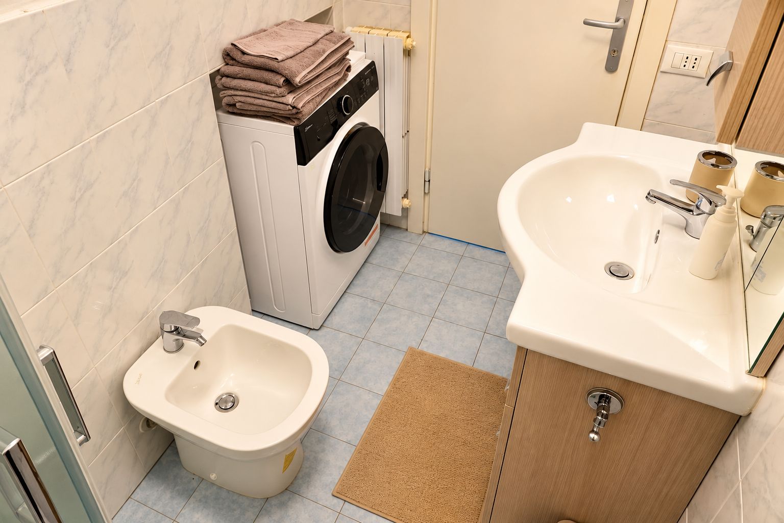 Une petite salle de bain équipée d’un lave-linge, d’un bidet et d’un lavabo.
