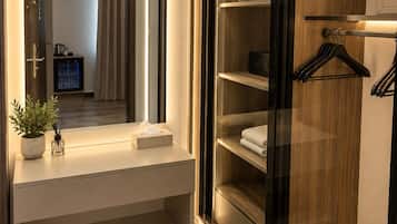 A modern bathroom with a vanity, a mirror, a towel rack, and a walk-in closet with shelves.