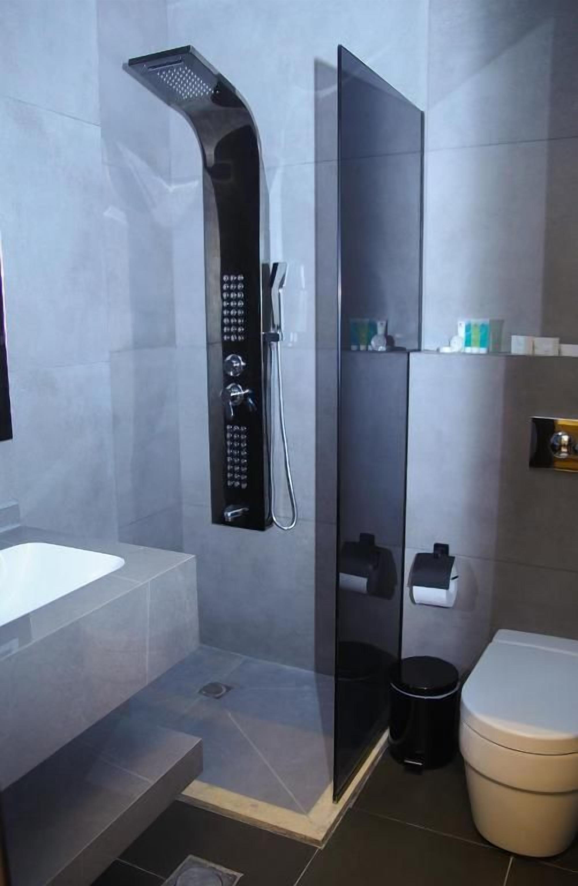 Ein modernes Badezimmer mit einer gläsernen Duschkabine, einem weißen Waschbecken und einer Toilette.
