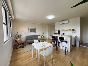 A compact living space with a dining area, kitchenette, and a sofa.