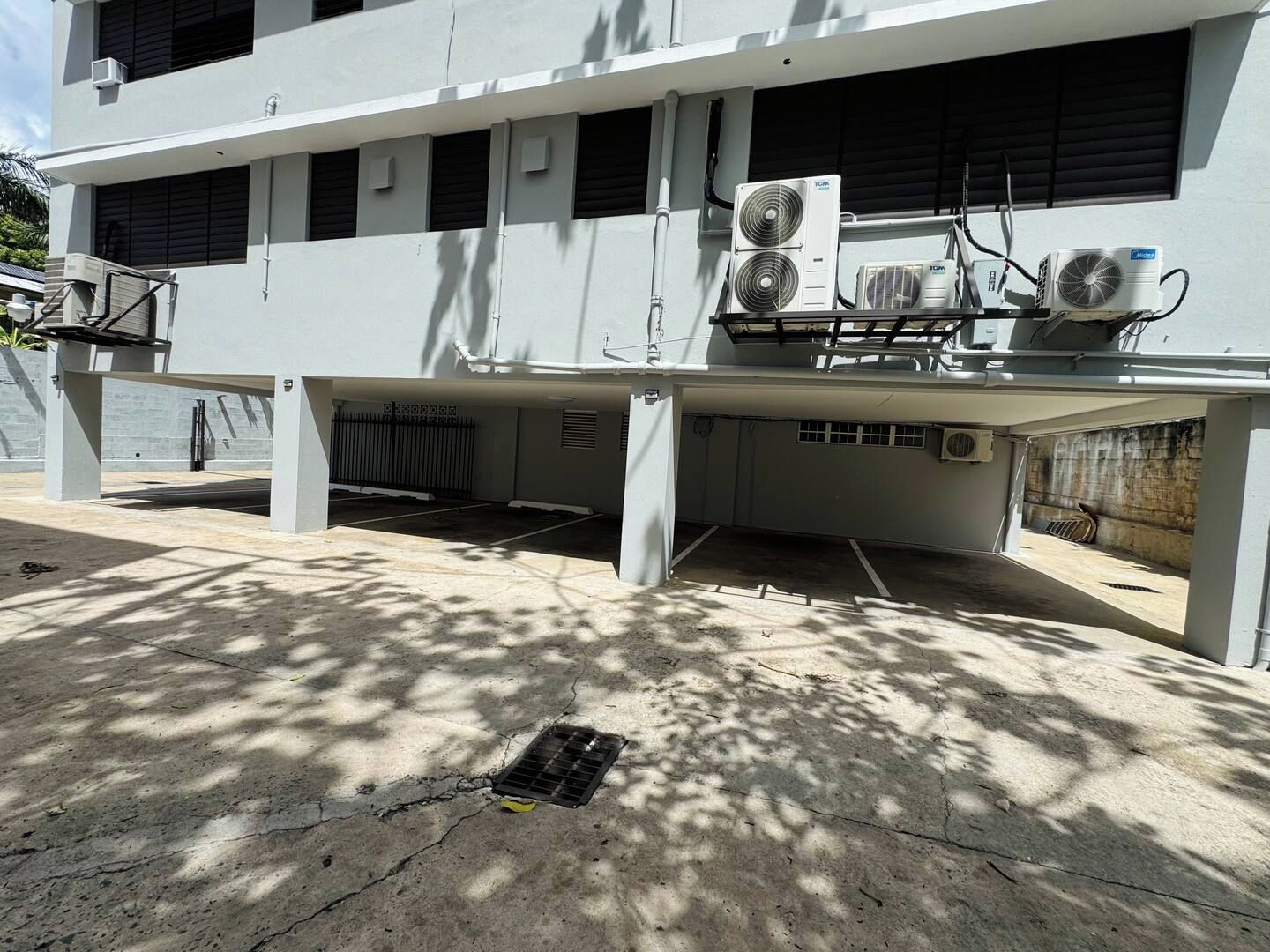 A building with multiple air conditioning units, a concrete floor, and a metal grate.