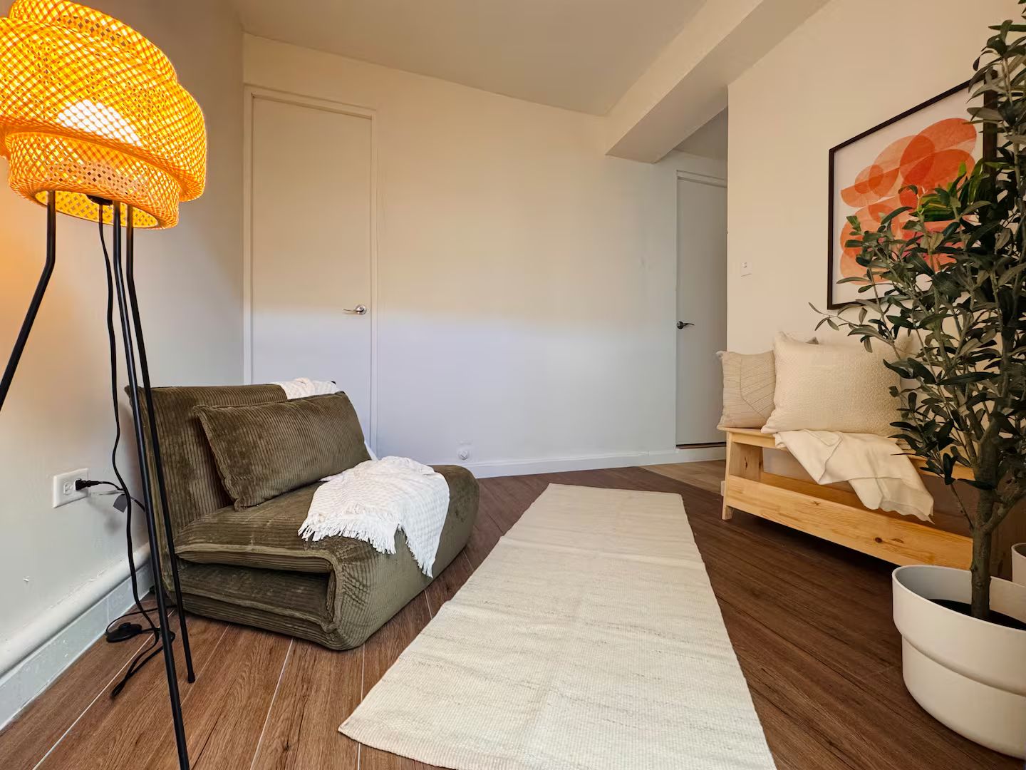 A living room with a sofa, a floor lamp, a rug, and a potted plant.
