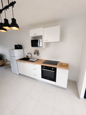 A modern kitchen with white cabinetry, a built-in oven, a microwave, and a black dishwasher. - Le Cocon du Palmier Bleu - Private Pool (Rivière-Salée)