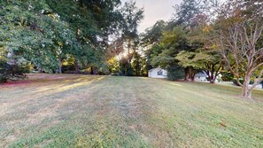 A grassy yard with trees and a small white building.