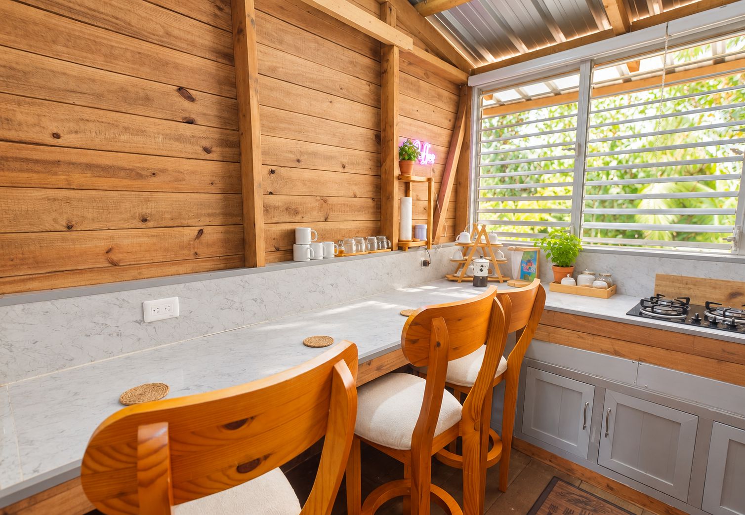 A kitchen with wooden walls, a white countertop, and a window with blinds.