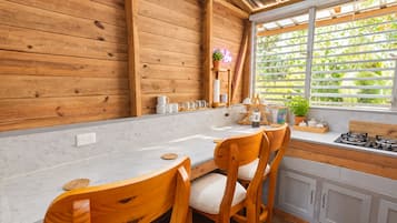 A kitchen with wooden walls, a white countertop, and a window with blinds.