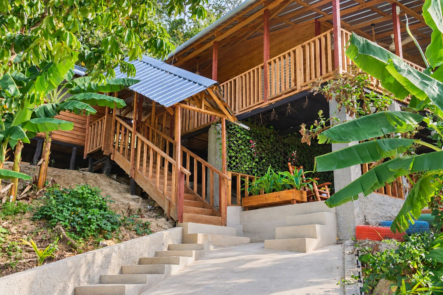 A wooden staircase leading to a covered porch with a metal roof, surrounded by lush greenery.