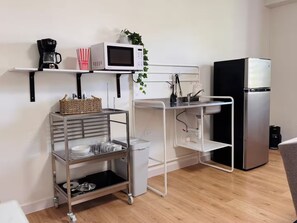 Eine kompakte Küchenzeile mit Mikrowelle, Kaffeemaschine und Kühlschrank.