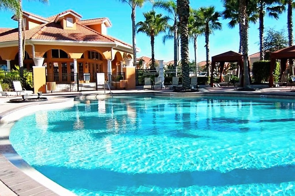 A swimming pool with lounge chairs and palm trees.