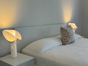 A bedroom with a bed, two bedside lamps, and a patterned pillow. - Central Apt in Historic Town San German - King Bed (San Germán)