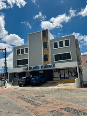 A modern building with a sign reading 'Island Finance' on the ground floor. - Central Apt in Historic Town San German - King Bed (San Germán)