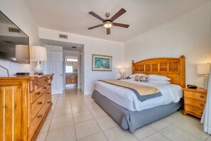A bedroom with a wooden bed, a ceiling fan, a dresser, and a painting on the wall. - Oceanfront with Beautiful Views! @The Reef Resort in beautiful East End (East End)