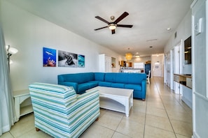 A living room with a blue sectional sofa, a striped armchair, and a white coffee table. - Oceanfront with Beautiful Views! @The Reef Resort in beautiful East End (East End)
