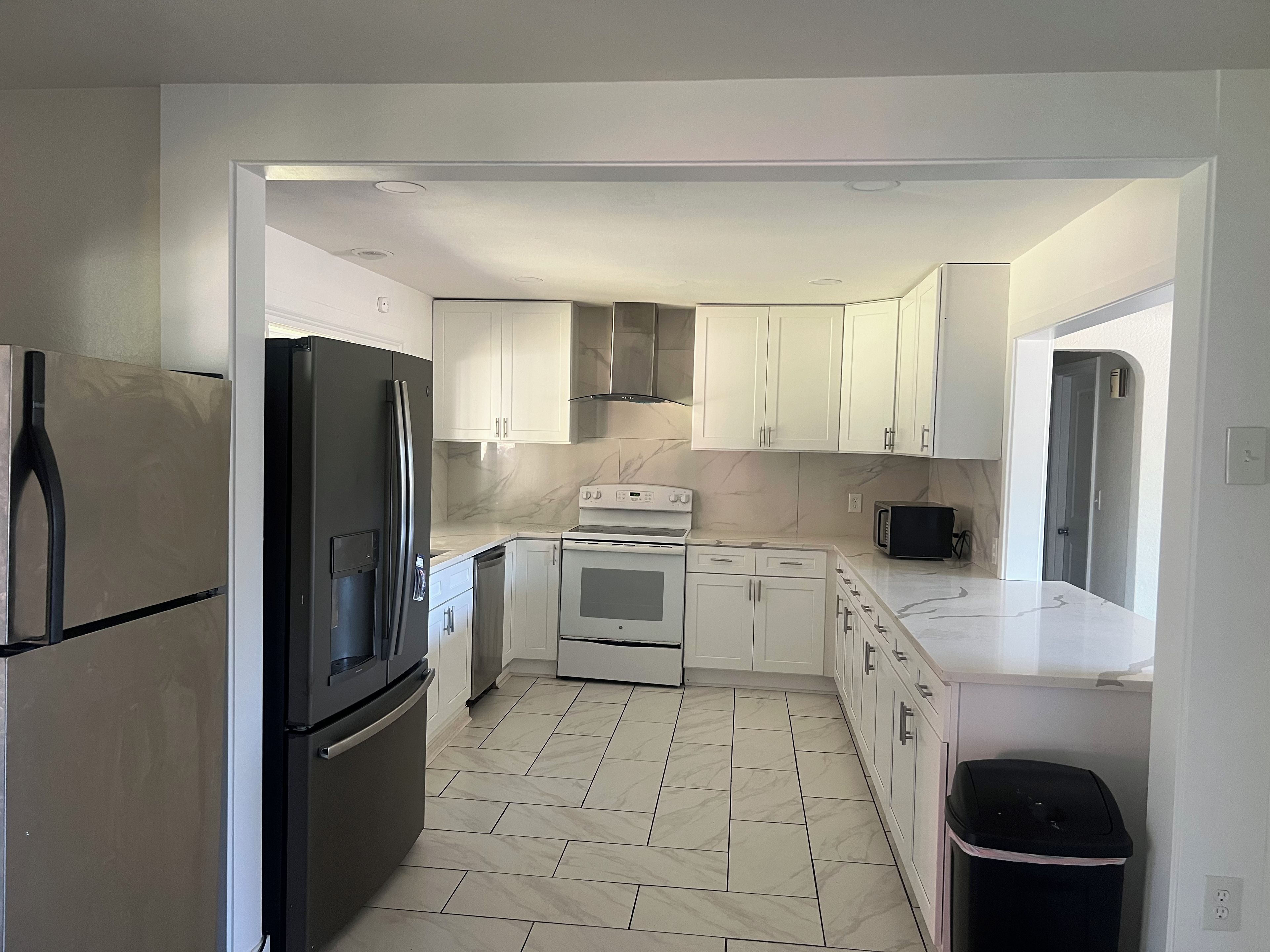 A modern kitchen with white cabinets, a black refrigerator, a stove, and a microwave.