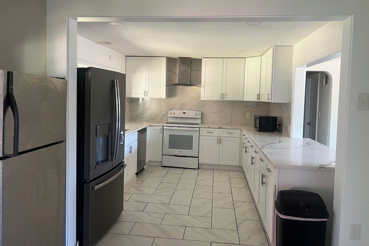 A modern kitchen with white cabinets, a black refrigerator, a stove, and a microwave.
