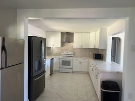 A modern kitchen with white cabinets, a black refrigerator, a stove, and a microwave.