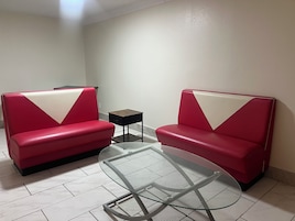 A room with two red sofas, a small black side table, and a glass-top coffee table.
