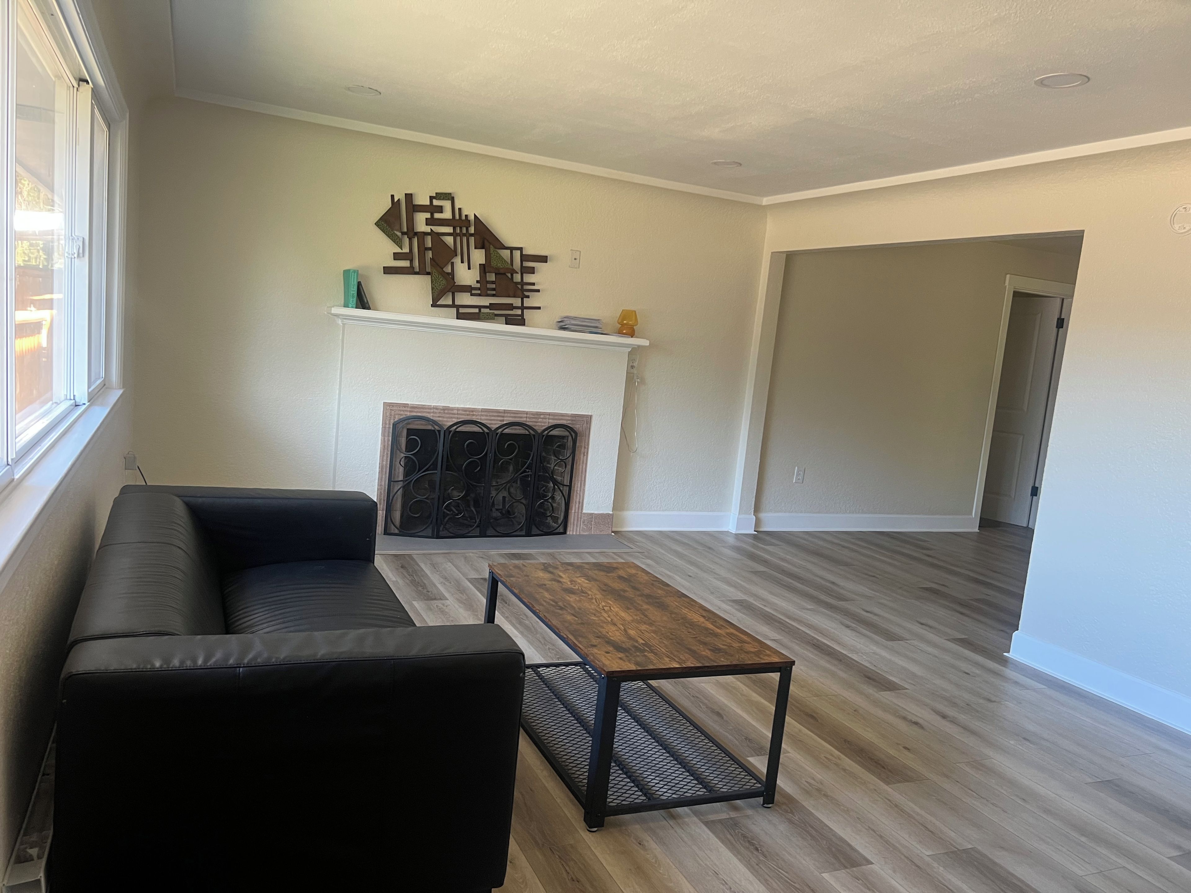 A living room with a black sofa, a wooden coffee table, and a fireplace.