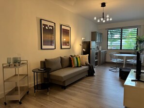A modern living room with a sofa, a small side table, and a dining area with a table and chairs. - Historic Stay in San Germán – Modern & Central (San Germán)