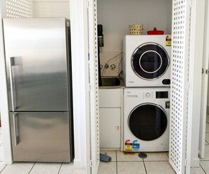 Een praktische keuken met een roestvrijstalen koelkast, een wasmachine en een magnetron.