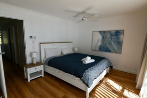 Ein Schlafzimmer mit einem Bett, Nachttischen, einem Deckenventilator und einem Gemälde an der Wand.