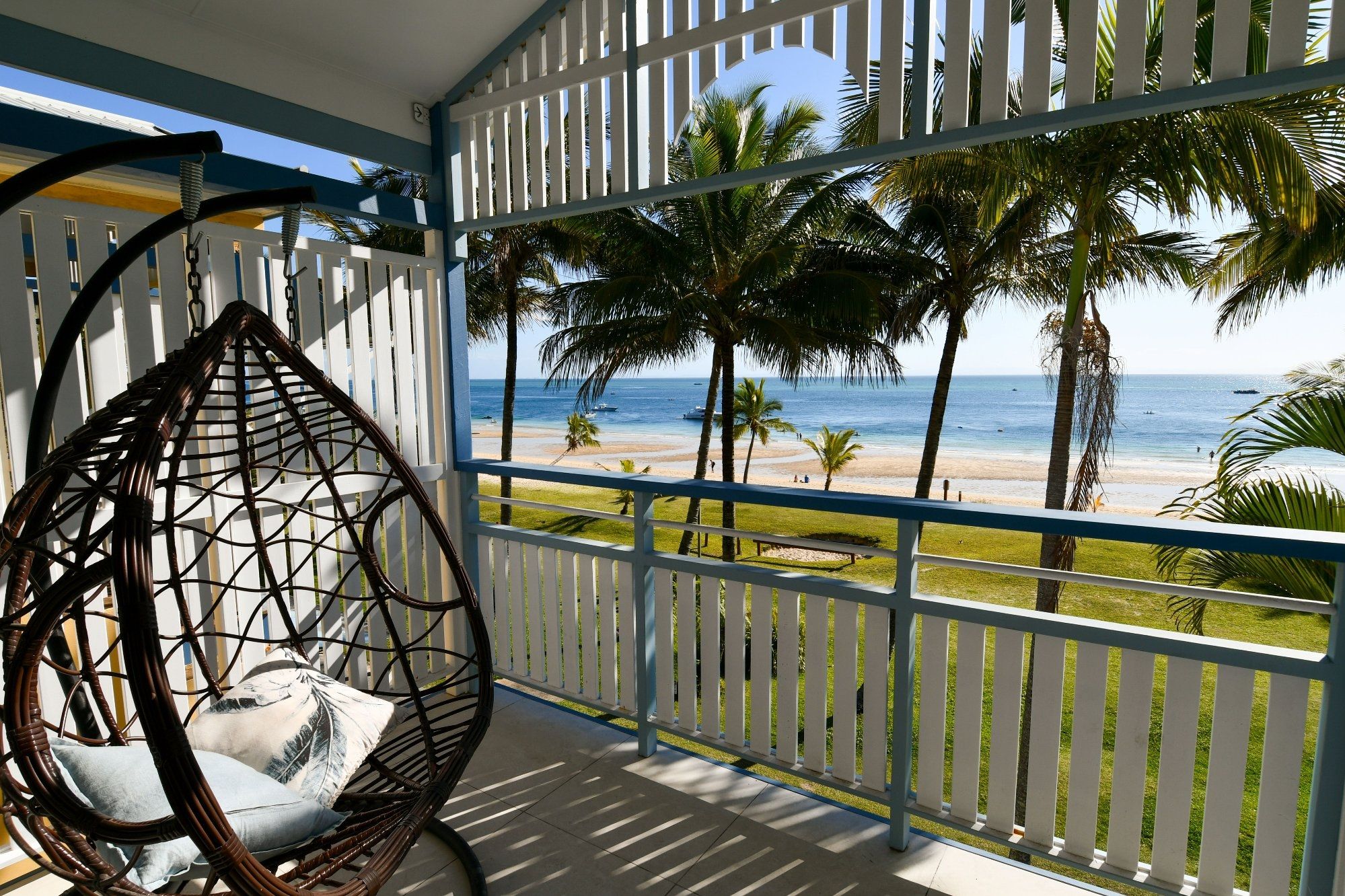 A balcony with a view of a beach and palm trees.