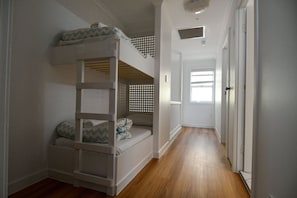 Ein Etagenbett in einem Flur mit Holzboden, Fenster und Tür.