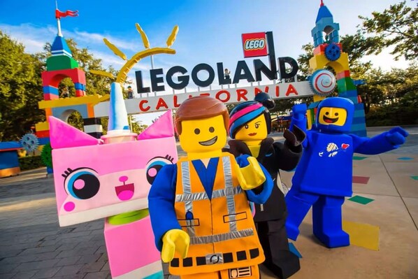 Uma entrada com tema LEGO, com uma placa indicando 'LEGOLAND CALIFORNIA' e estruturas coloridas de LEGO.