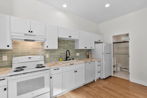 A modern kitchen with white cabinetry, a built-in oven, and a sink. - Vista Compound | Walk to Downtown/Shops/Dining (Vista)