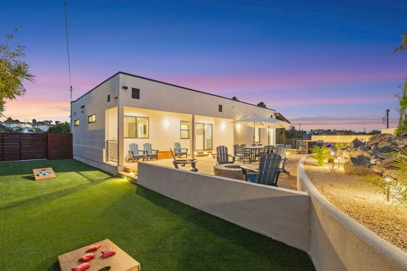 A modern two-story house with a patio area, outdoor seating, and a well-maintained lawn.