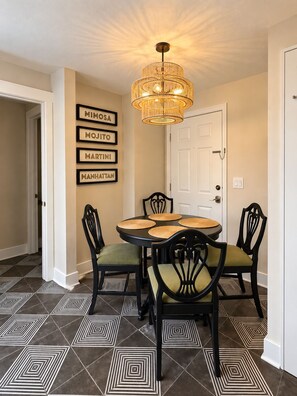 A dining area with a round table, chairs, a chandelier, and a wall with framed names. - NEW! Brickhouse Villas. 2 blocks from UF. Early check in/late check out. Parking (gainesville)