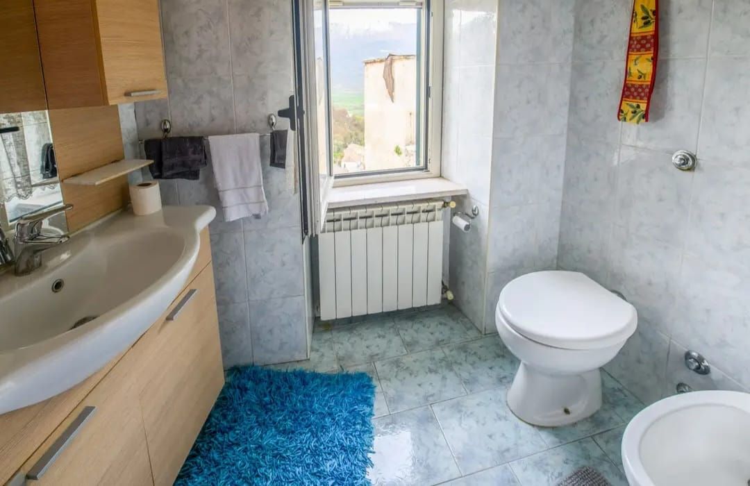 A bathroom with a bathtub, toilet, and a window.