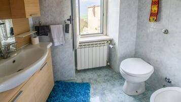 A bathroom with a bathtub, toilet, and a window.