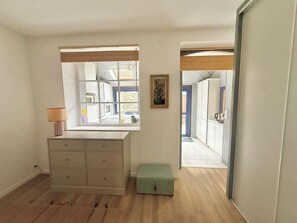 Ein Zimmer mit Fenster, einem Schminktisch, einer Lampe und einer kleinen, grünen Schachtel.