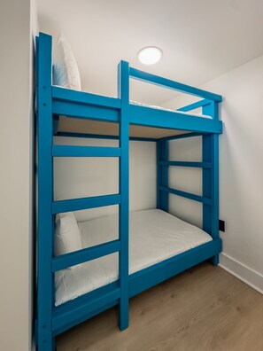 Ein Stockbett mit blauem Gestell und weißer Bettwäsche.