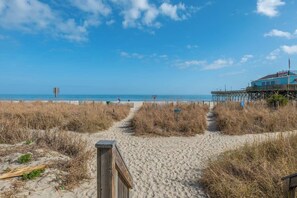 A beach path leading to a pier with a building on stilts. - Modern Oceanfront Escape at Yachtsman! S900 (Myrtle Beach)