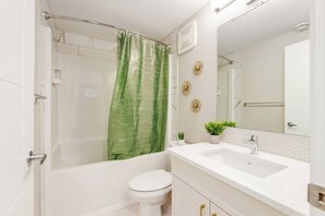 Een badkamer met een douche, toilet, wastafel en spiegel.