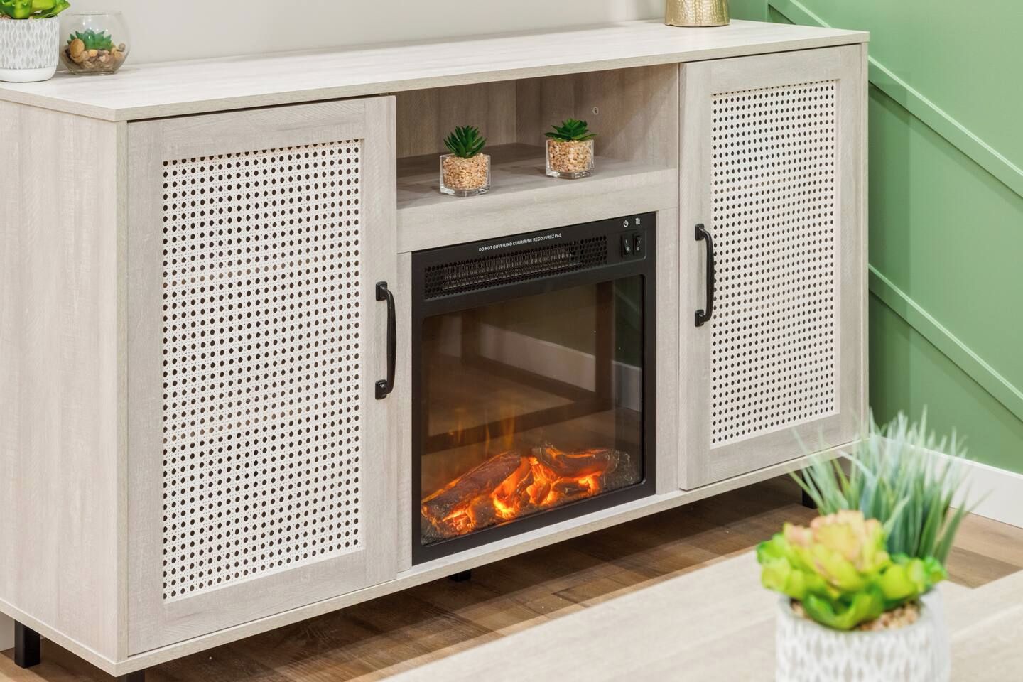 A wooden cabinet with a glass-fronted fireplace, two small potted plants on top, and a handle on the right side.