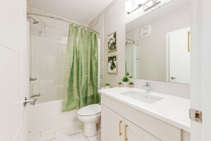 Ein Badezimmer mit Dusche, Toilette, Waschbecken und Spiegel.